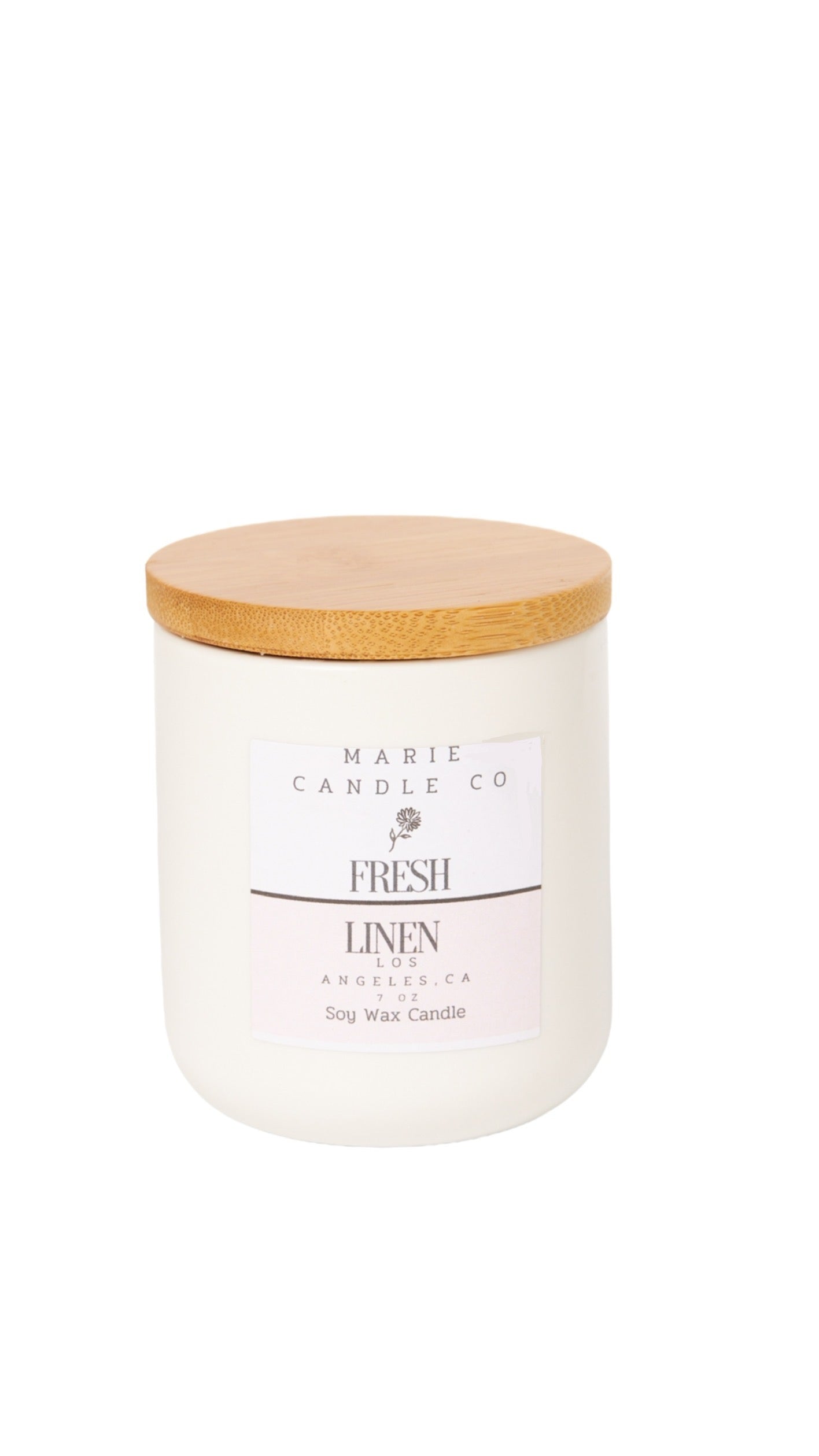 A clear soy wax candle with a beige label that reads 'MARIE candle co. Fresh Linen'.